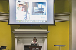 Katherine Pratt at the podium with  screened images above her